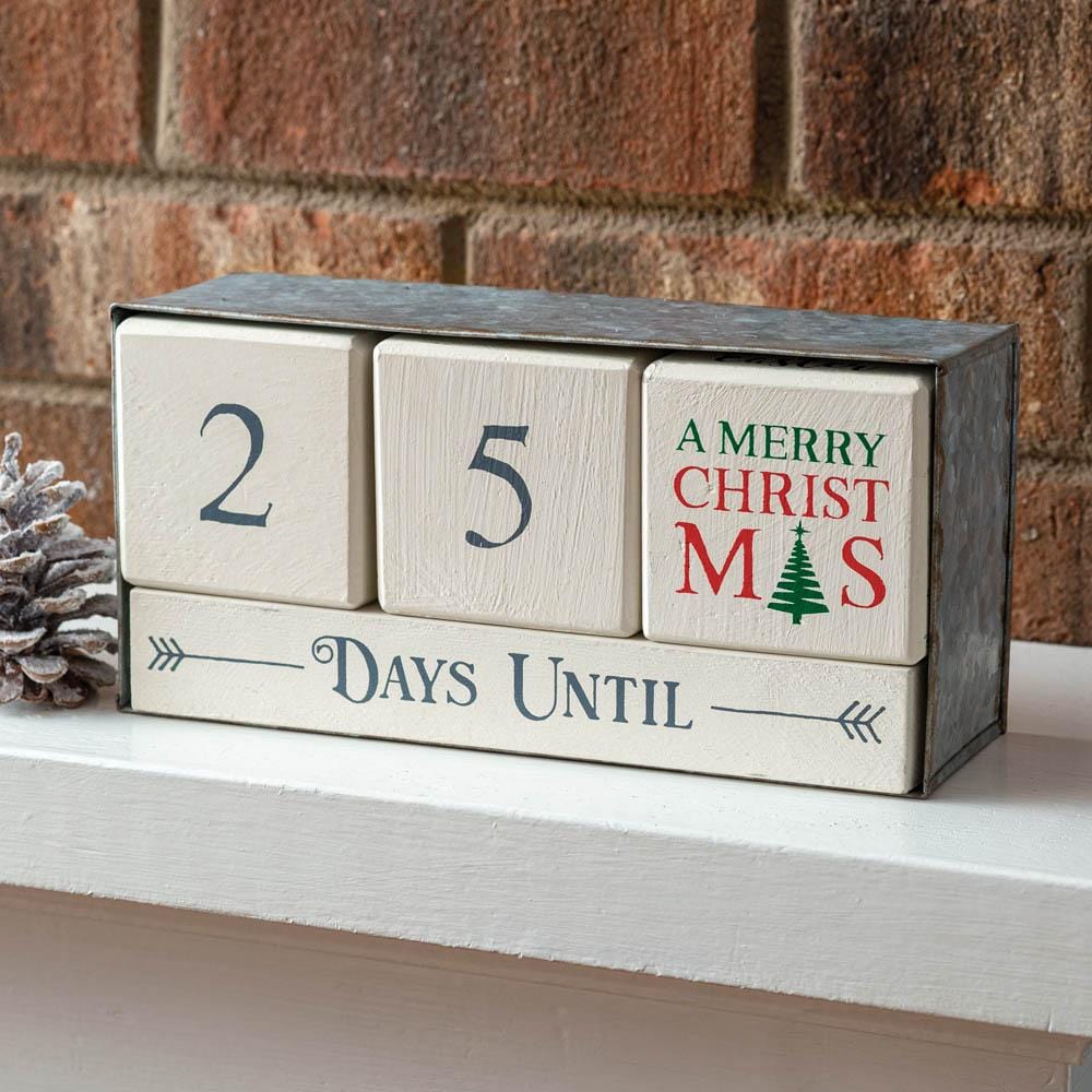 Wooden block calendar with metal box, featuring numbered blocks for holiday countdowns, displayed on a festive tabletop.