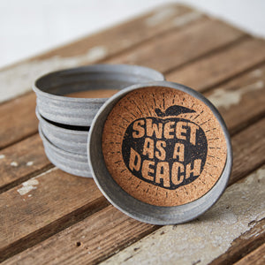 A set of four Mason Jar Lid Coasters with a vibrant peach print, featuring cork interiors to absorb moisture and protect surfaces.