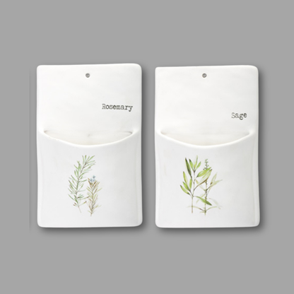 Two white pouches with botanical illustrations and labels for 'Rosemary' and 'Sage' on a gray background.