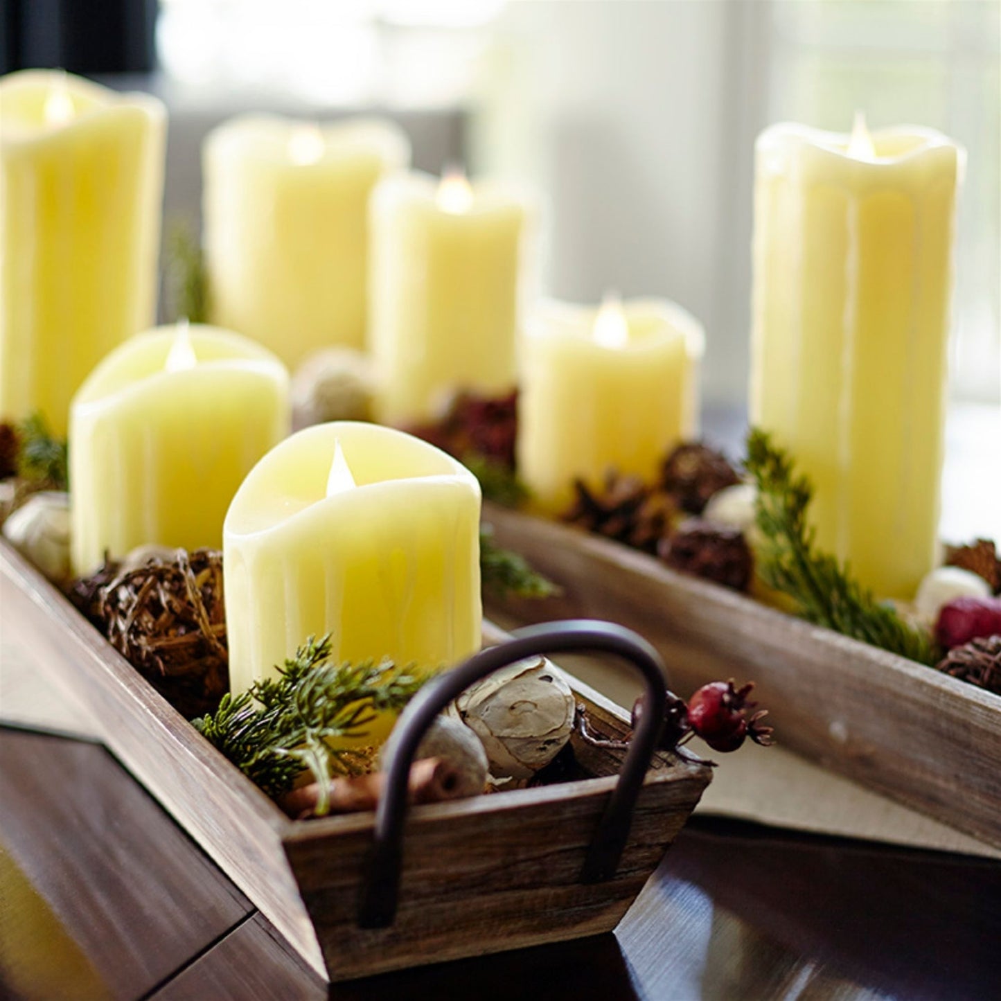 Decorative arrangement of candles and natural elements in a wooden tray.