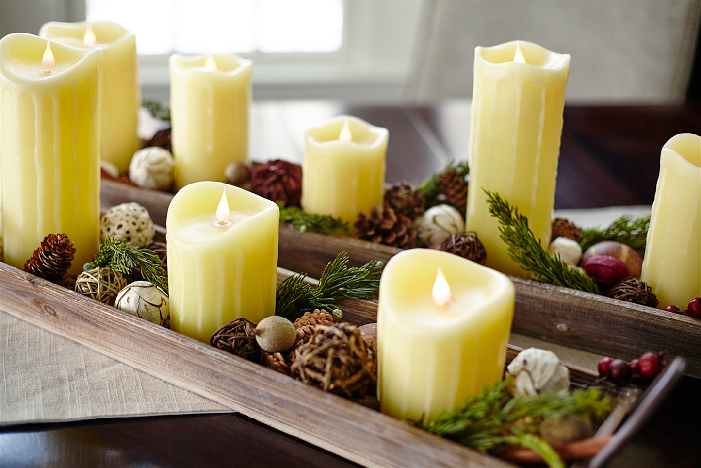 Decorative arrangement of lit candles and natural elements on a wooden tray.