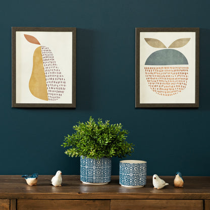 Two framed abstract artworks on a dark blue wall with a wooden shelf featuring decorative items.
