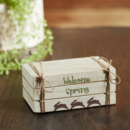 Cream faux book stack decor with Welcome Spring text, hand-painted bunnies, and soft farmhouse spring charm.