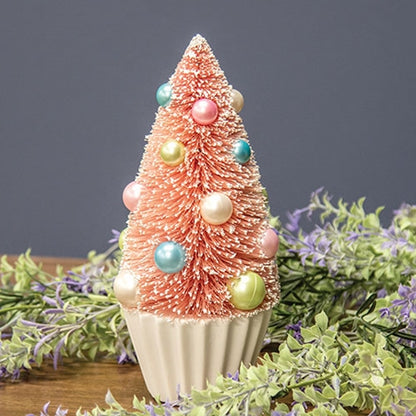 Pink Bottle Brush Tree with faux snow, pastel baubles in blue, pink, green, white on a pleated white base for festive decor.