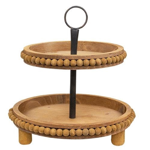 Natural wood two-tiered tray with round bead detailing, black metal center dowel, and three wooden legs for a farmhouse look.