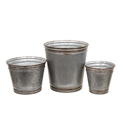 Set of three round galvanized silver metal planters with distressed copper edges, filled with vibrant plants on a porch.