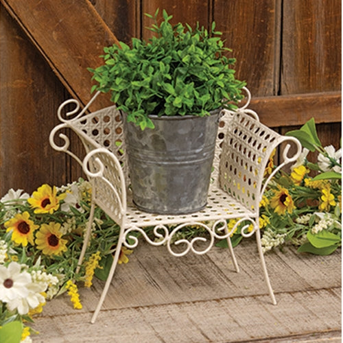 Cream-colored metal garden chair planter stand with lattice design, vintage style, and swirling flourishes on curved legs.