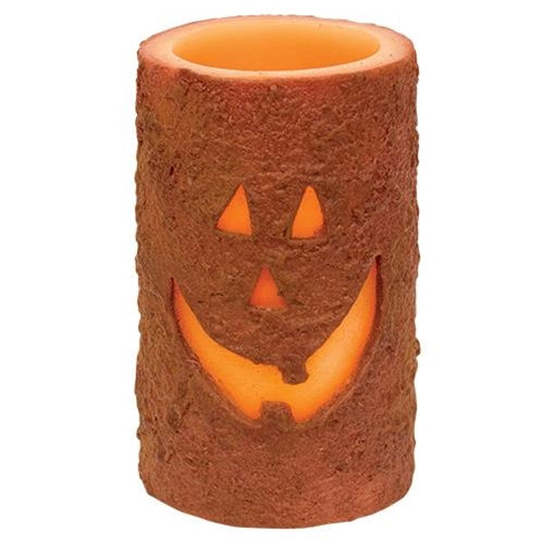 Battery-operated LED jack-o'-lantern pillar candle with grungy wax finish and warm Halloween glow