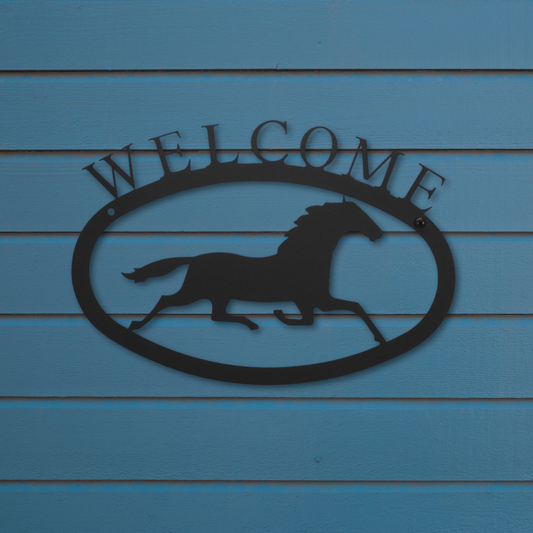 Metal 'Welcome' sign with a horse silhouette on a blue wooden background