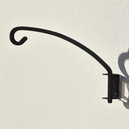 Black metal planter bracket with curved arm on a beige wall