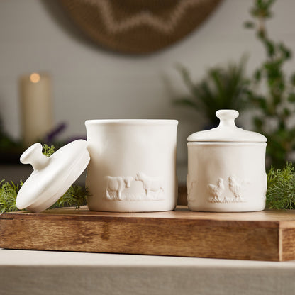 White ceramic canisters with farm animal accents, featuring chickens and cows, perfect for a farmhouse-style kitchen.